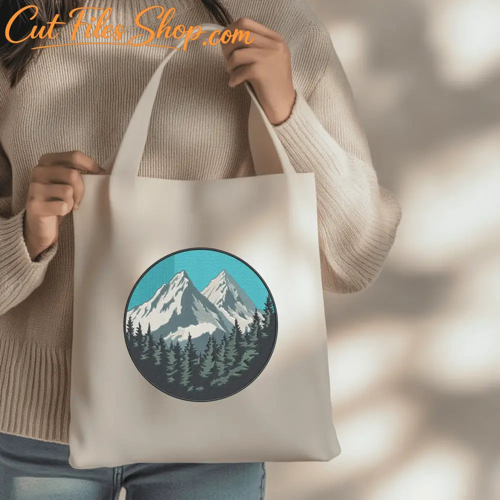 Detailed alpine embroidery scene featuring mountain clouds and a dense evergreen forest.